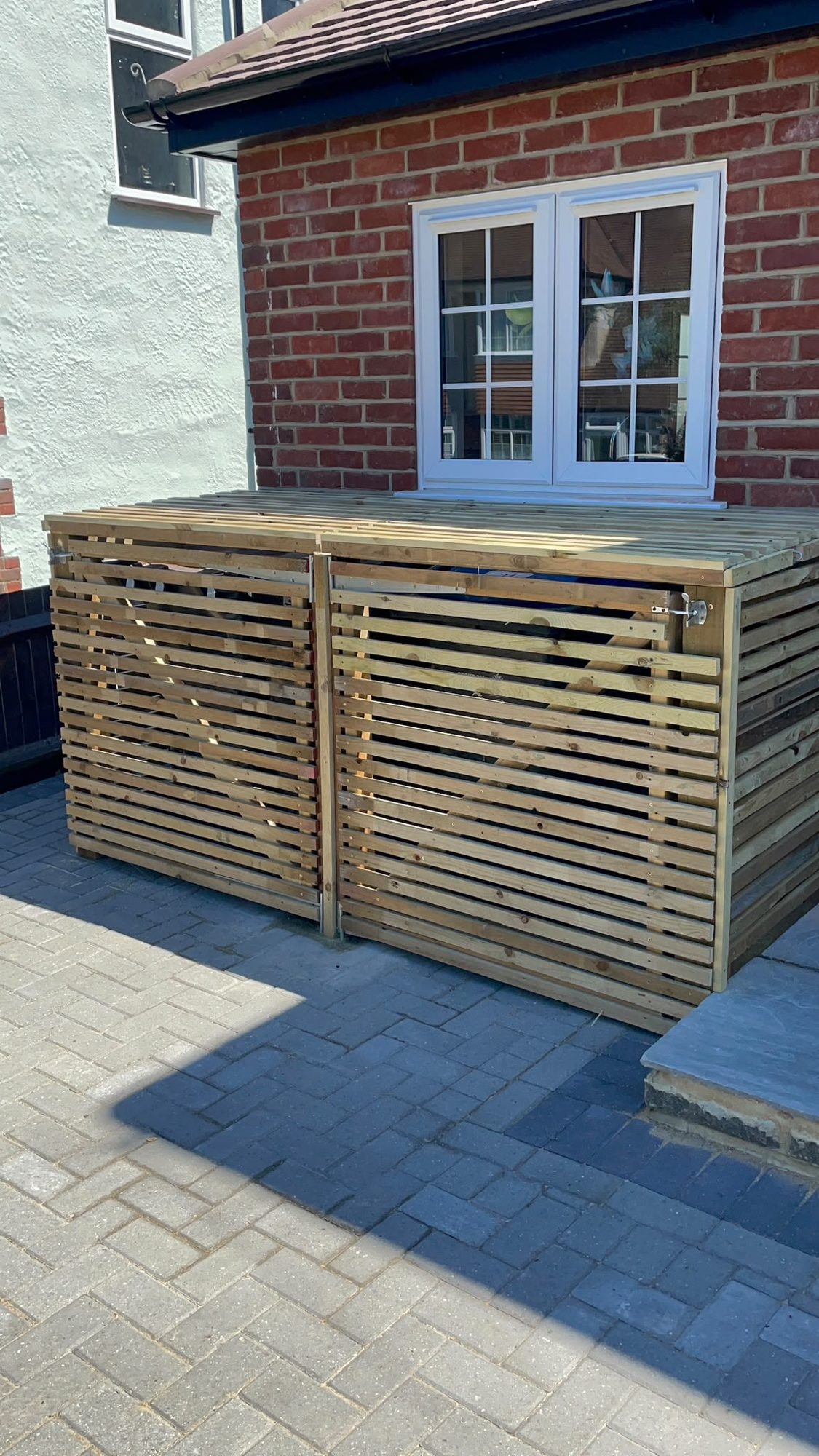 Timber slatted bin store on a block paved driveway