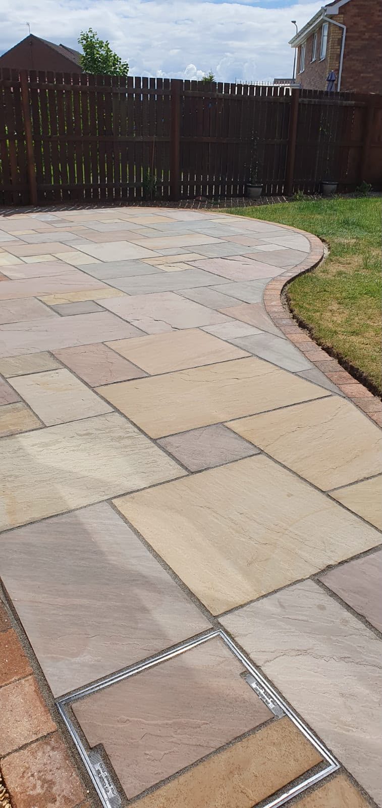 Curved Indian sandstone patio edge meeting the lawn
