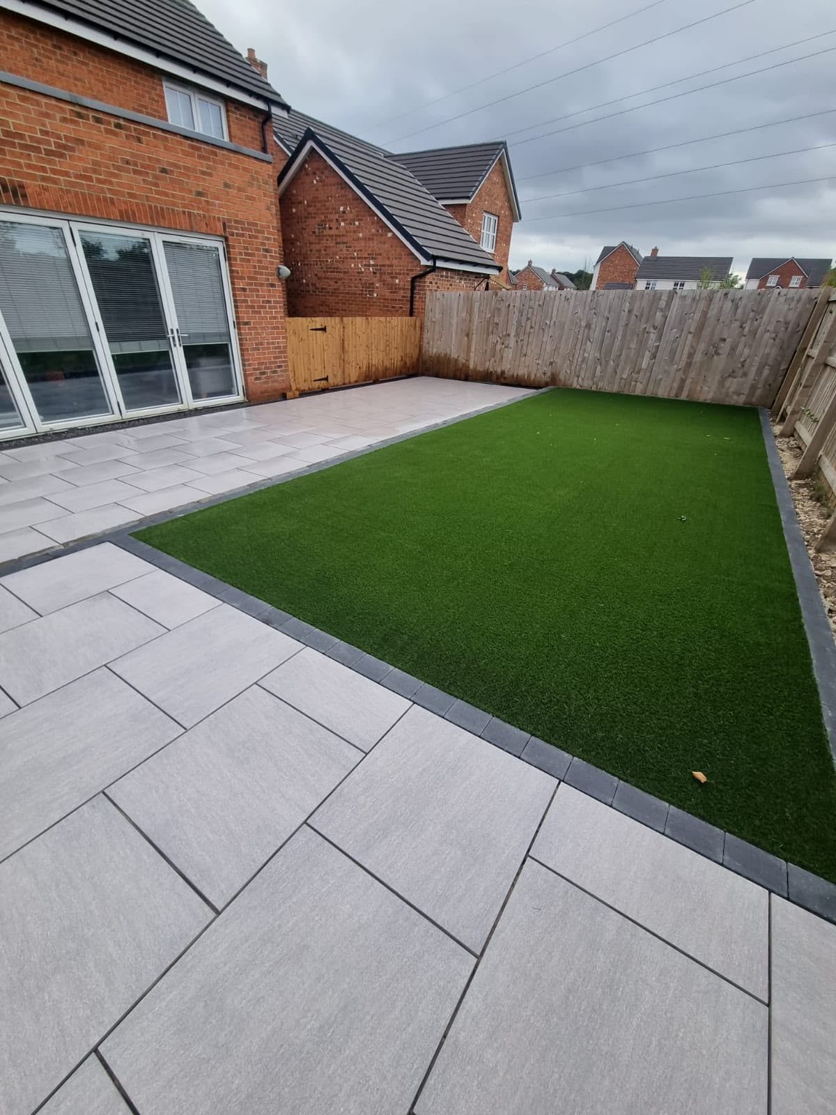 Grey porcelain patio with artificial grass lawn in a new-build garden