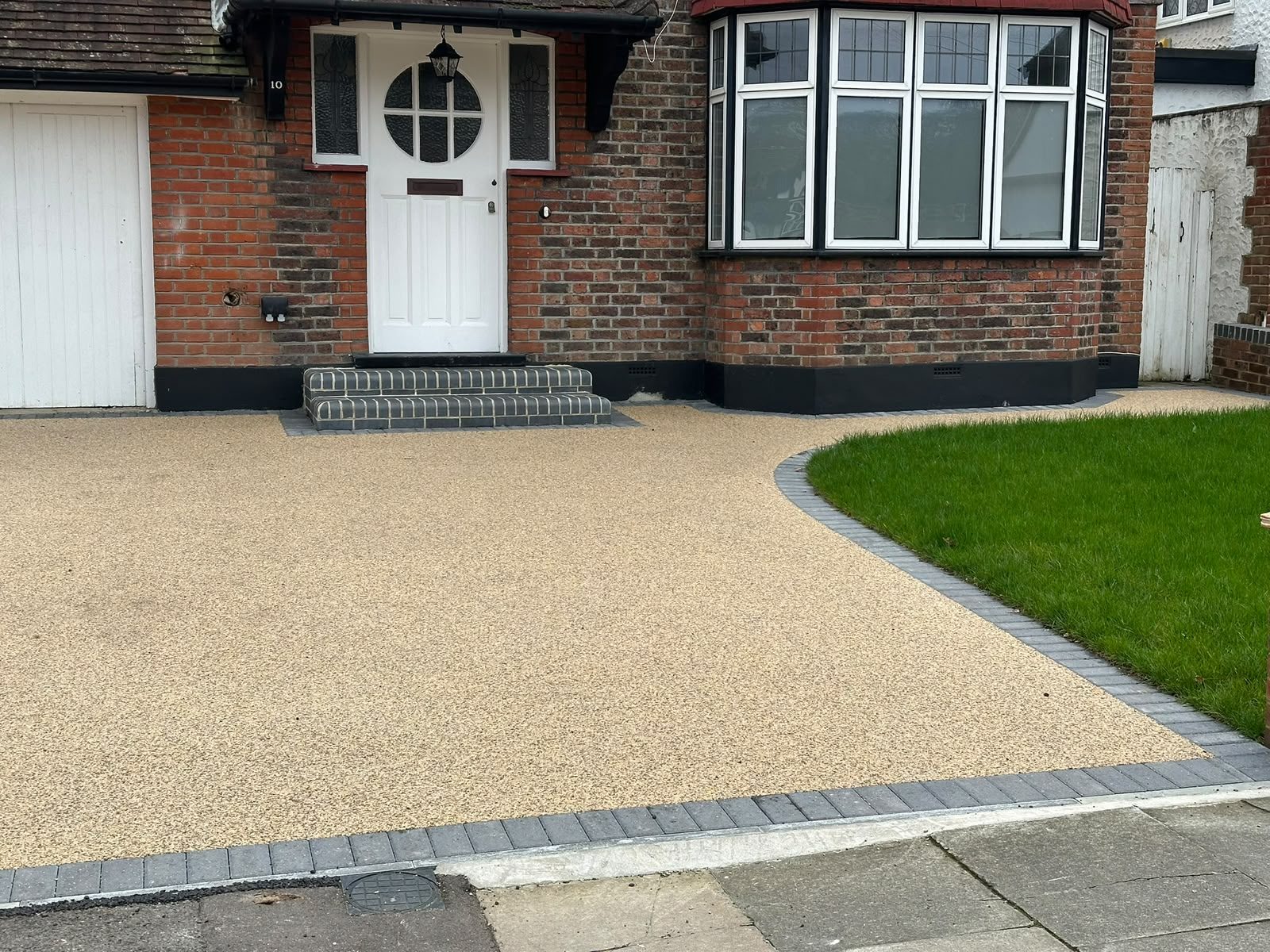 Close view of a smooth resin bound driveway with charcoal block edging and lawn