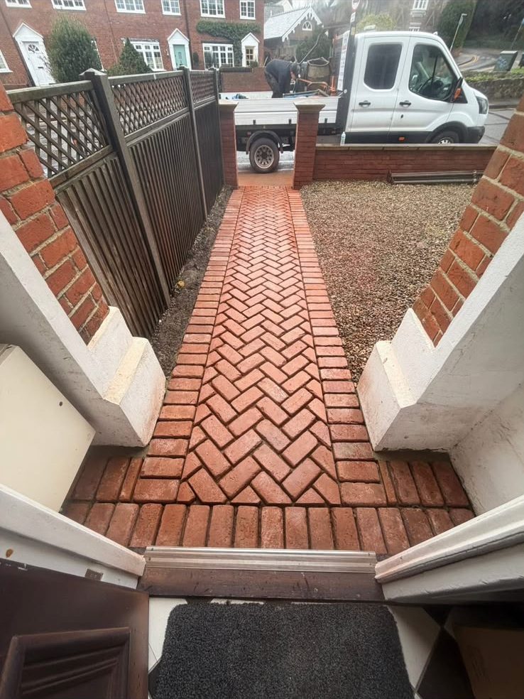 Herringbone red brick garden path viewed from the front door towards the street
