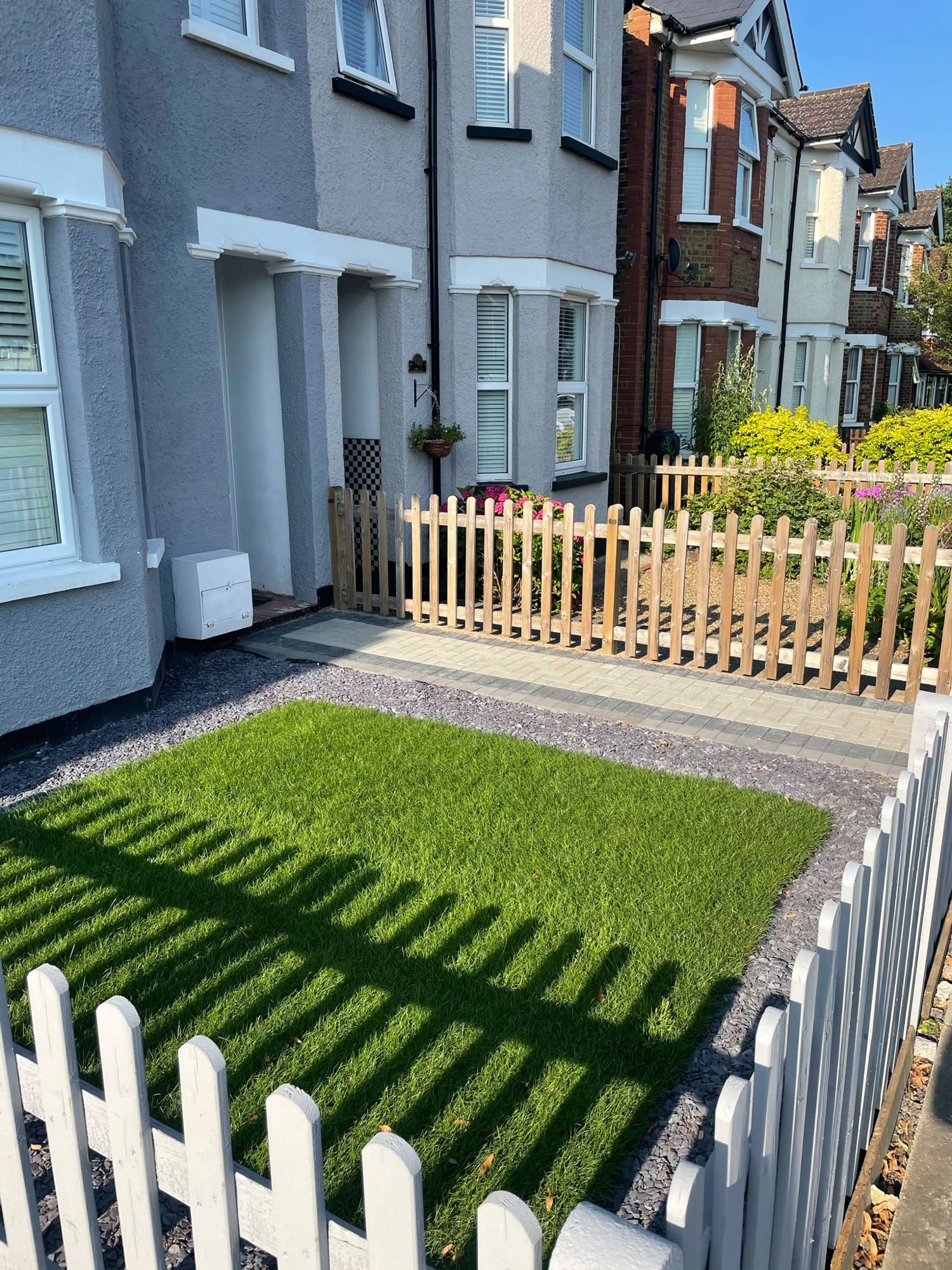 Timber picket fencing around a front garden with artificial grass