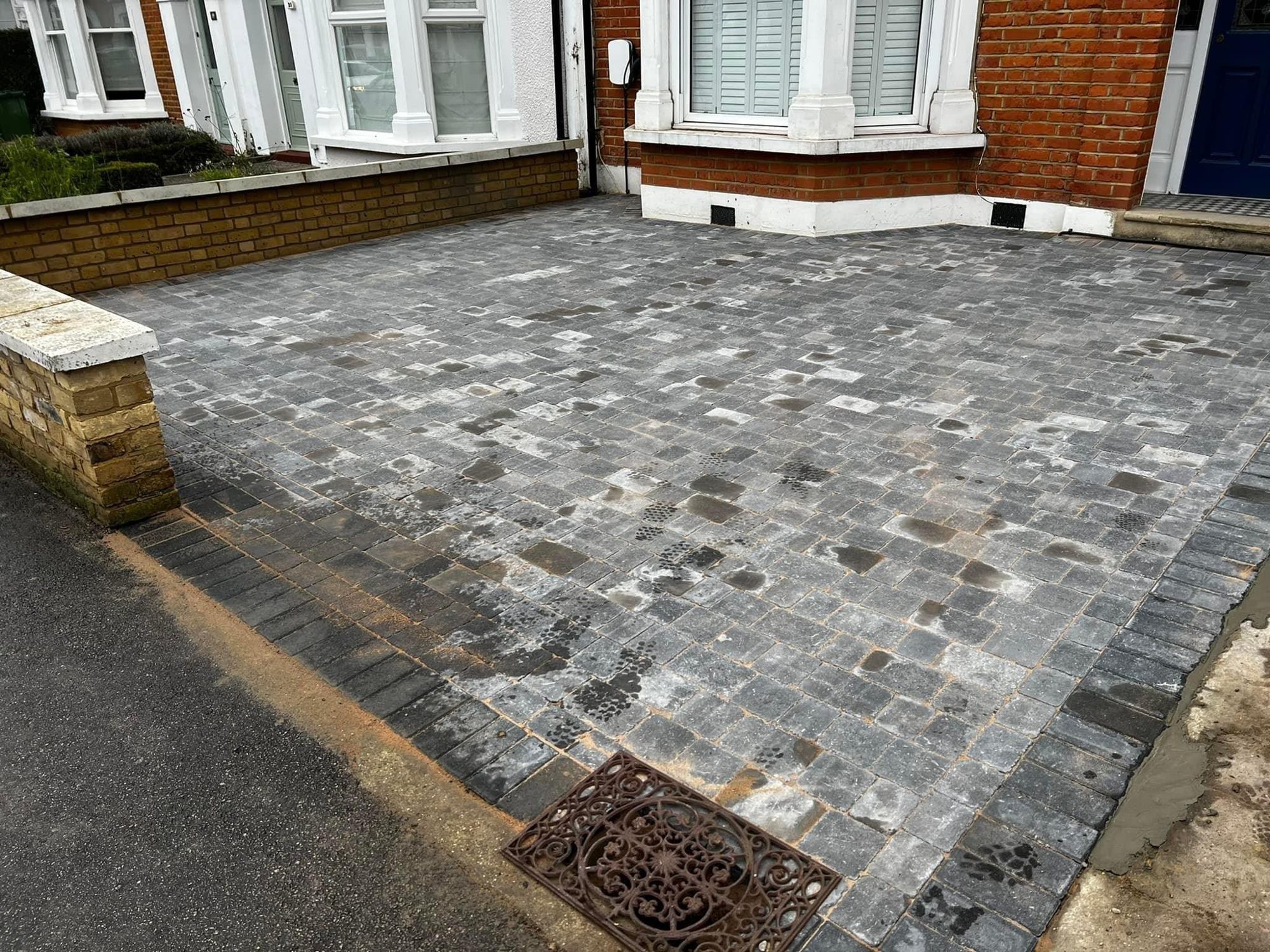 Grey and charcoal block paving driveway with drainage grate, newly laid