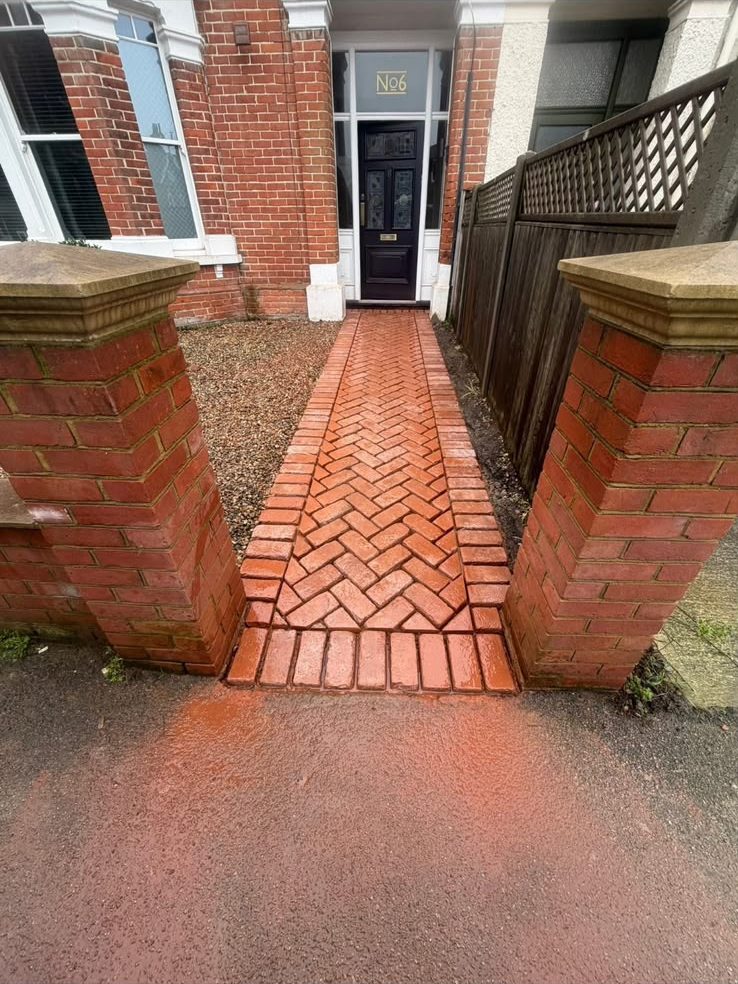 Red herringbone brick front path between brick piers leading to a terrace front door