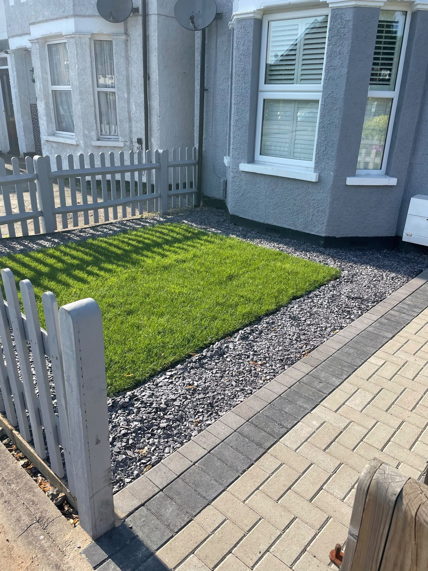 Block paved front path beside new lawn, slate chippings and picket fencing